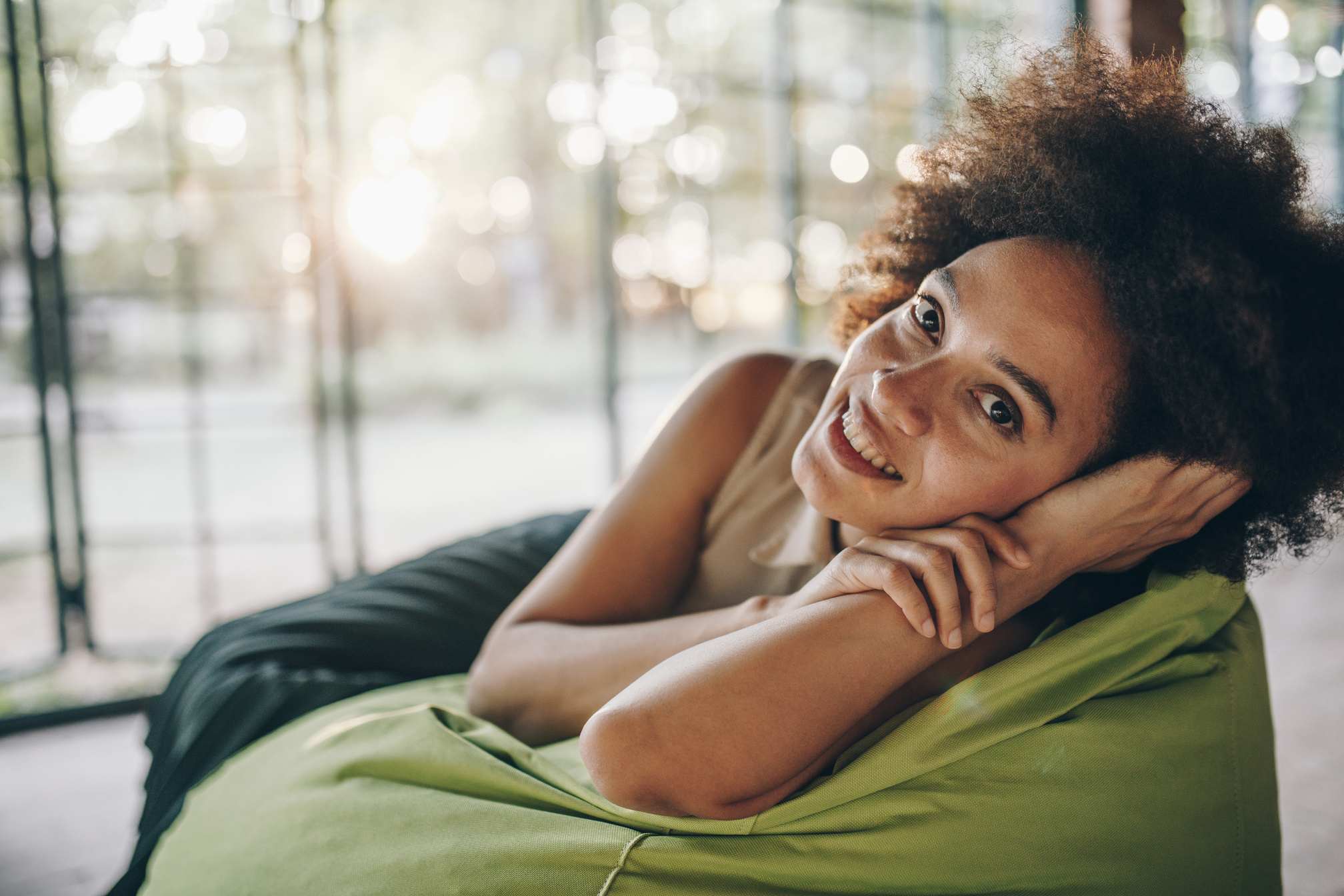 Young happy black woman relaxing on a bean bag.